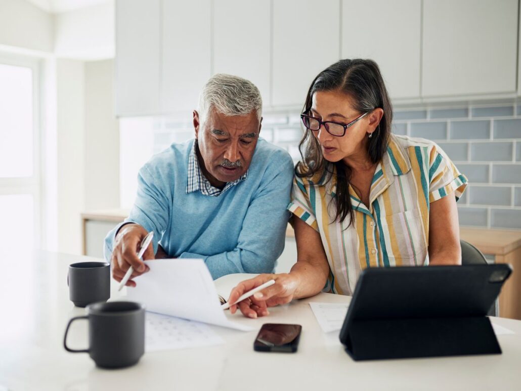 Two adults seated at a table at home reviewing documents together